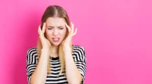 Young woman feeling stressed on a pink background